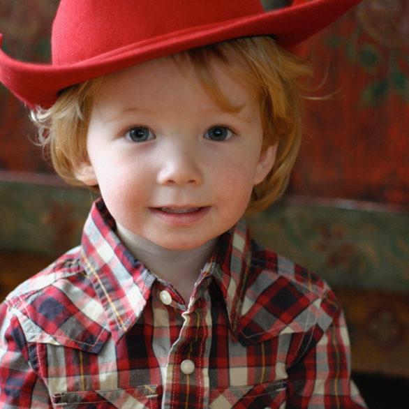 Young Charlie with a red cowboy hat on.